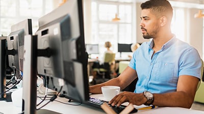 Man dressed in business casual attire sitting at a desk using a computer