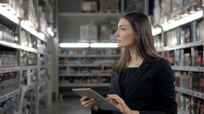 Woman dressing in business attire holding a laptop and looking at inventory.