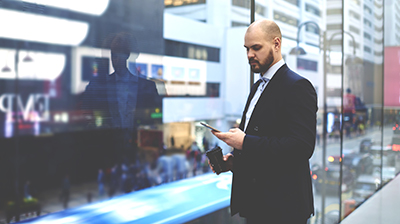 Man using his phone and holding a disposable coffee mug.