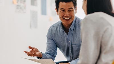  A man and a woman smiling while looking at a piece of paper