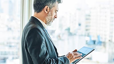 Man using tablet device while standing at window