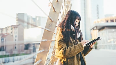 A young woman working on her tablet outside