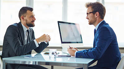 Two business men talking to each other across a desk