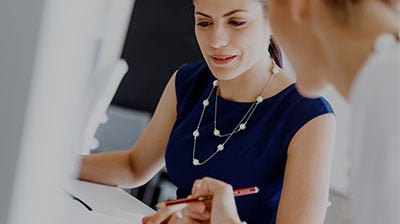 Two business women comparing notes on a tablet