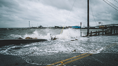 Waves crashing over a fence onto a road