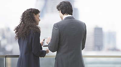 Two young business people standing outside while working together on a tablet