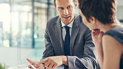 Two colleagues dressed in business attire conversing.